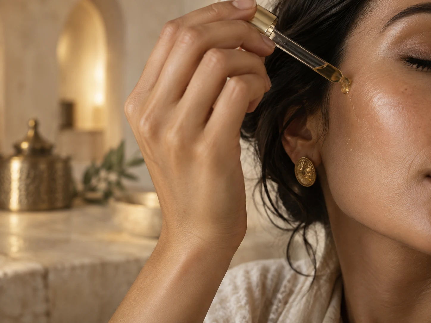 mains adultes appliquant quelques gouttes d’huile sur le visage